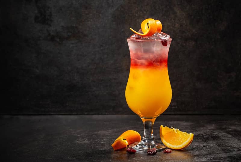 Un cocktail sex on the beach avec des tranches d'orange sur fond sombre.