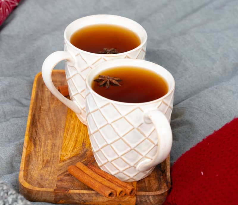 Deux tasses de thé sur un plateau en bois avec des bâtons de cannelle.